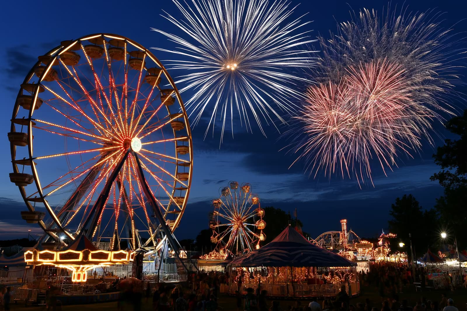 Un luna park illuminato a giorno con una grande ruota panoramica e giostre, che si anima al crepuscolo sull'Heiligengeistfeld di Amburgo.