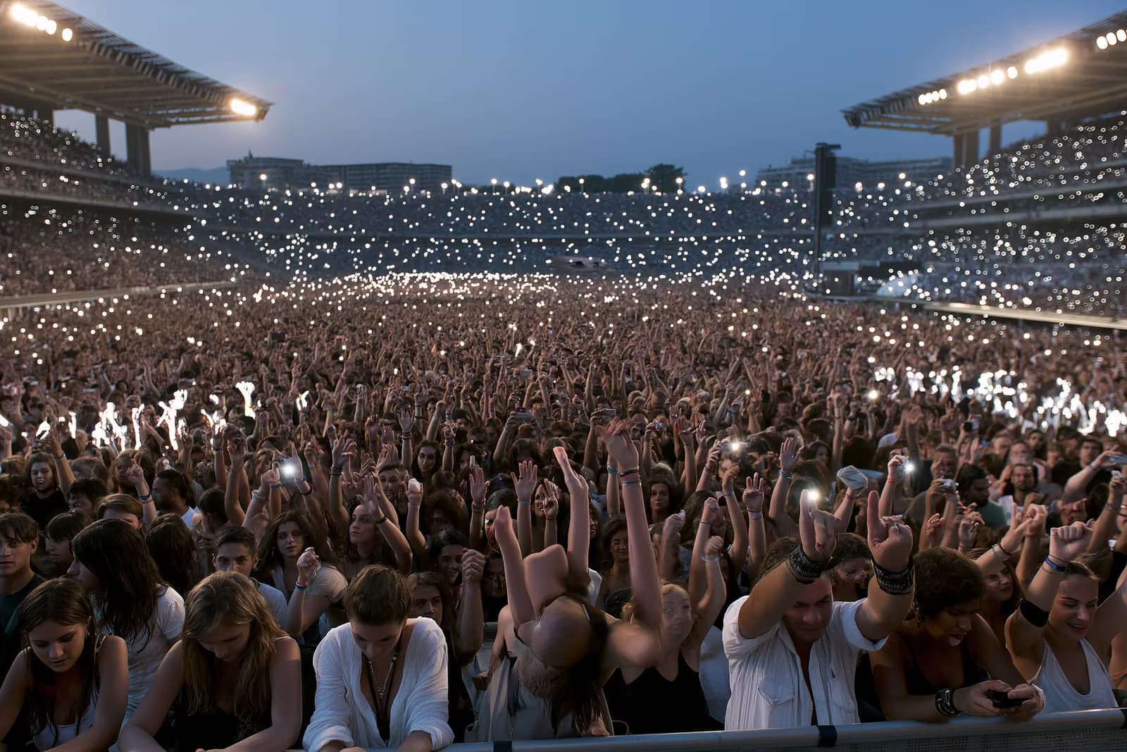 Una grande folla in uno stadio illuminato dalla luce del tramonto durante un concerto estivo a Monaco di Baviera.